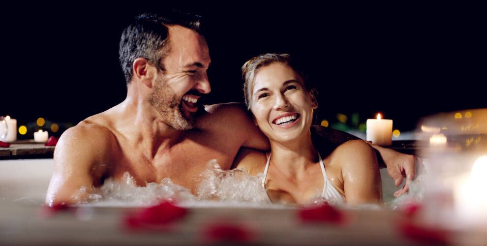 Glückliches Paar in einem Whirlpool im Ferienhaus